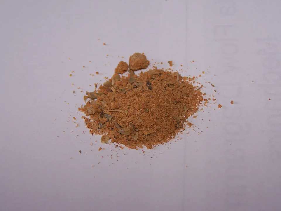 A close view of a reddish Cajun spice mixture with visible dried herbs.